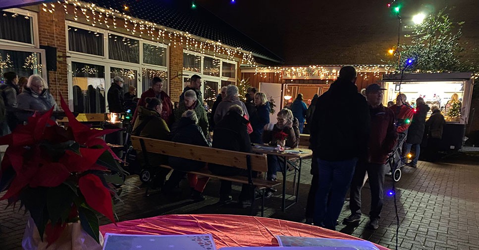 Ein Adventsmarkt im winterlichen Dunkel mit Sitzgelegenheiten und Ständen. 