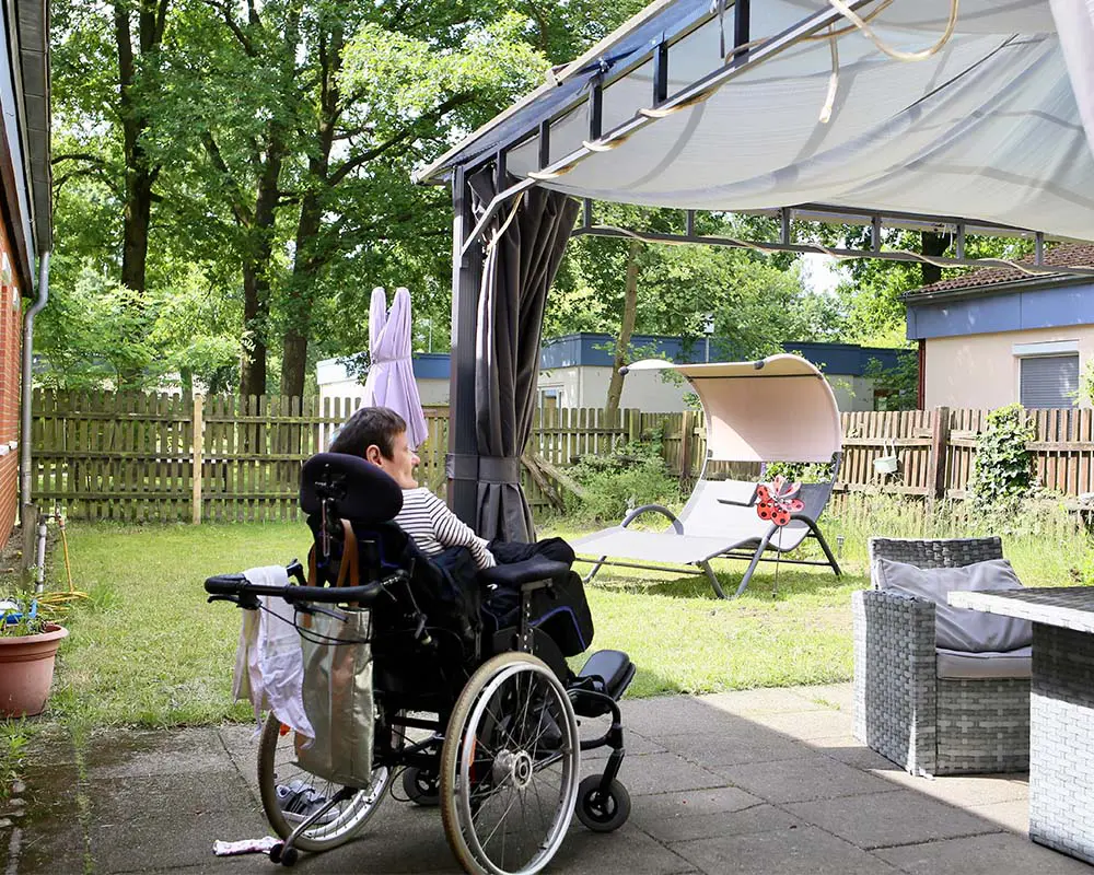 Ein Mann im Rollstuhl steht im Garten einer Wohngemeinschaft