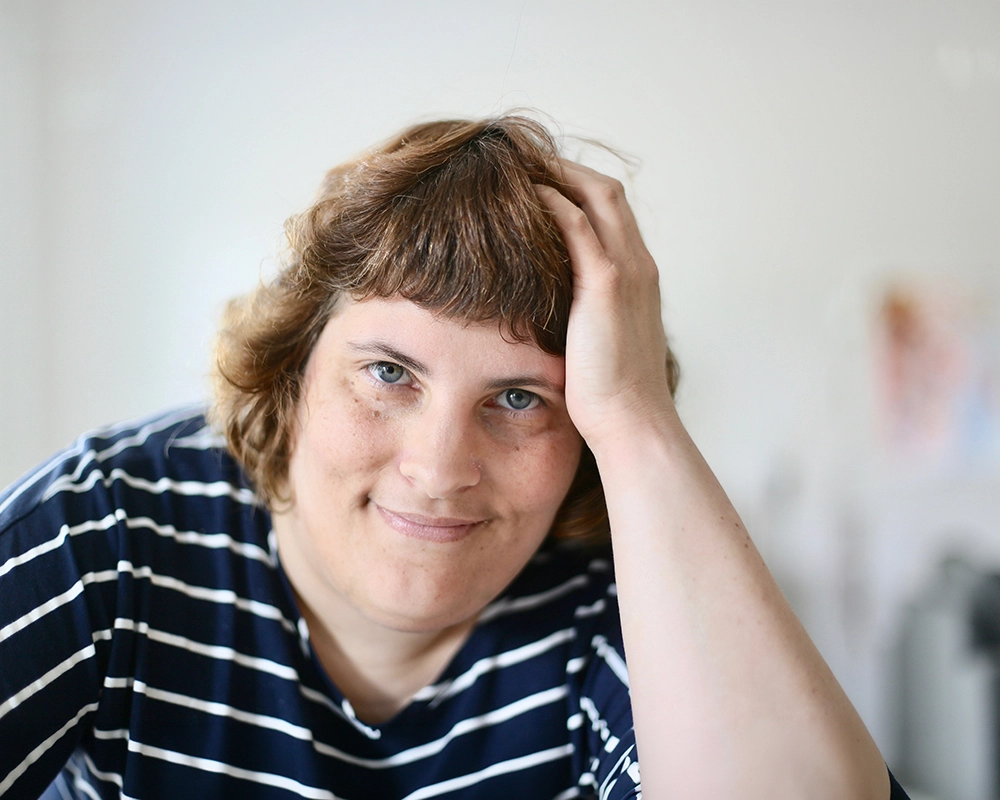 Eine Mitebwohnerin der Wohngemeinschaften stützt sich mit der Hand am Kopf ab.